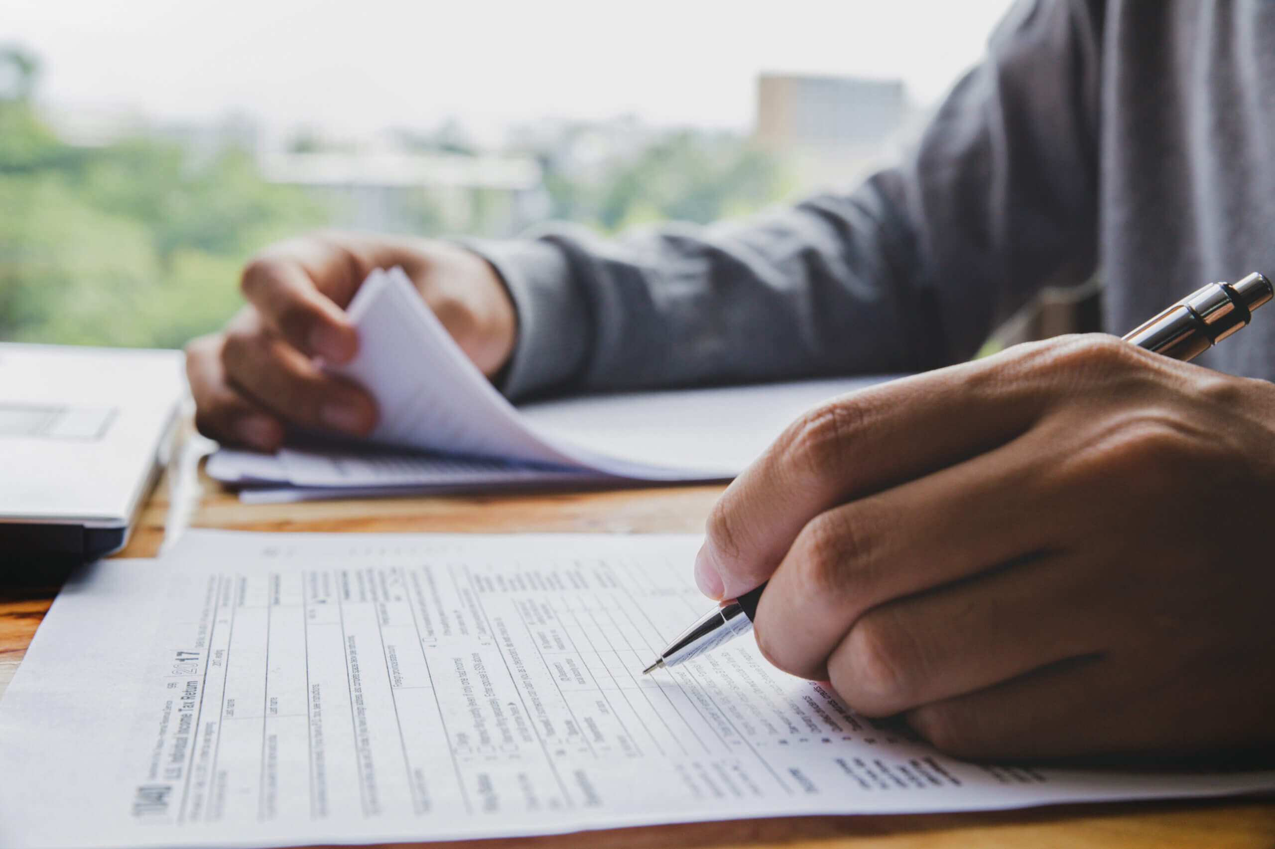 A person is filling out papers with a pen.
