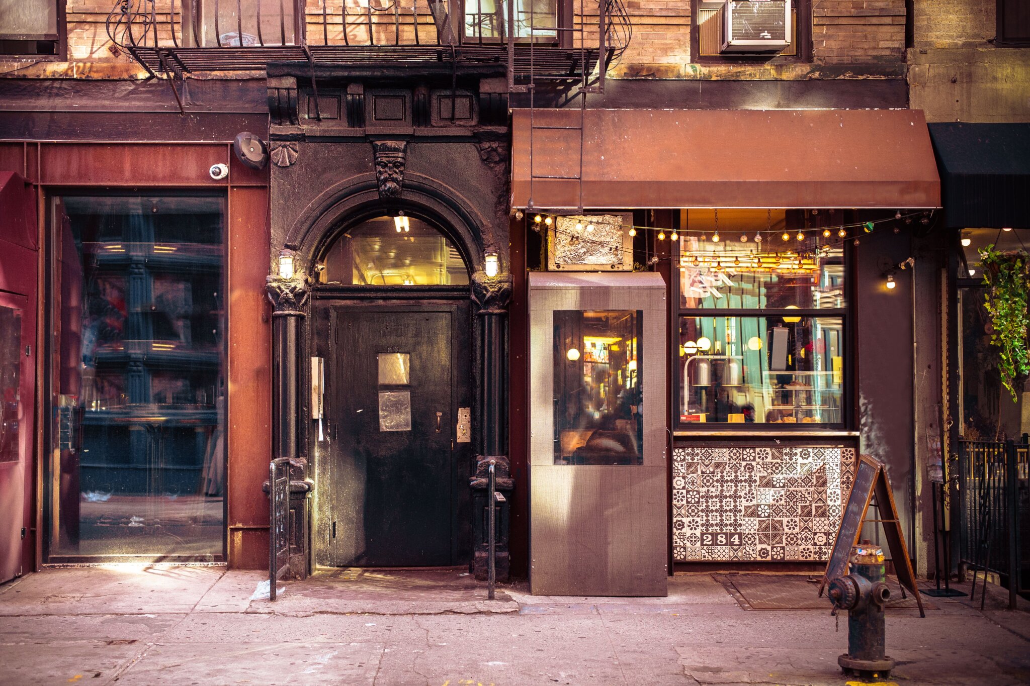 Store front with a large window and a large arched black door.