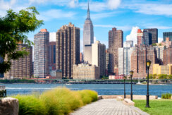 The midtown Manhattan skyline in New York City on a summer day as seen from a beautiful park in Queens.