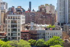 New York City - Overhead view of historic buildings along 59th Street with the Midtown Manhattan skyline in the background with blue skies.