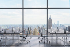 Workspace in a modern panoramic office, filled with lack tables and black leather chairs, with a view of New York city view from the large windows.